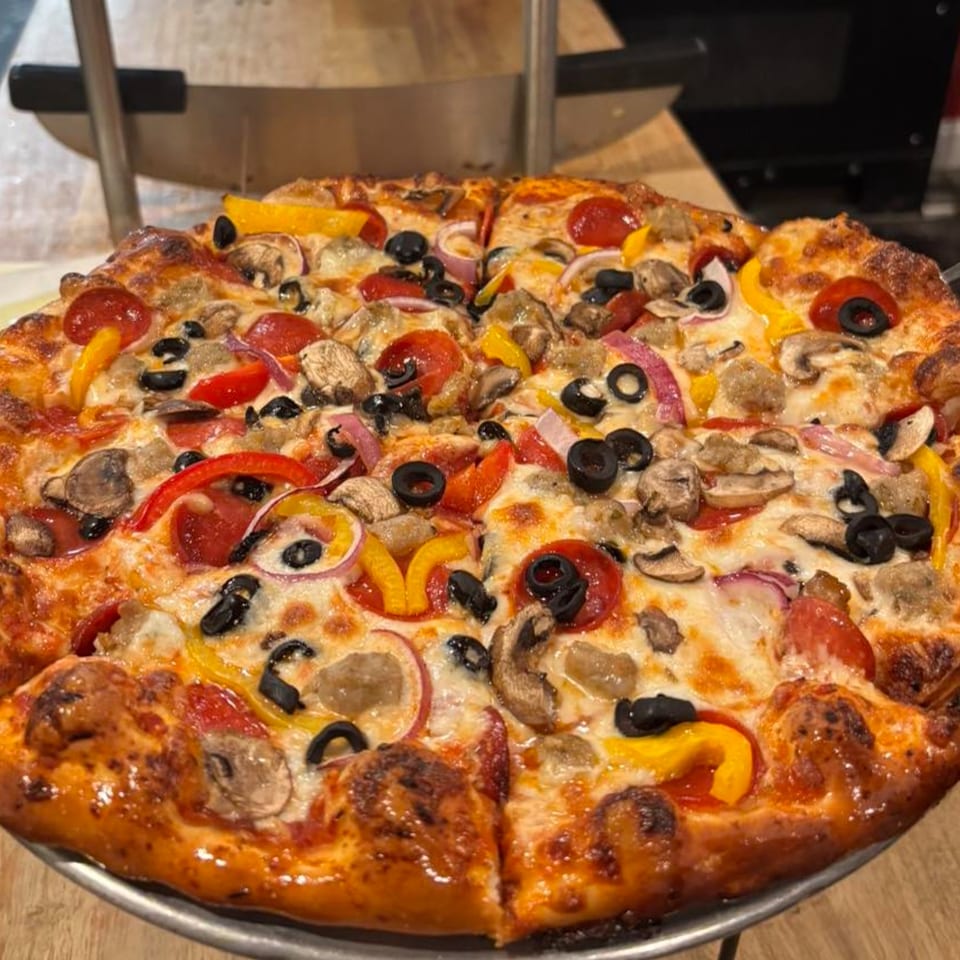 A freshly baked Bourbon Street Pizza with pepperoni, mushrooms, olives, and bell peppers.