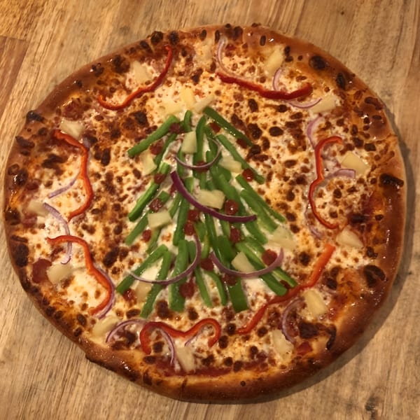 Bourbon Street Pizza with a Christmas tree design made from green peppers, red peppers, and onions.